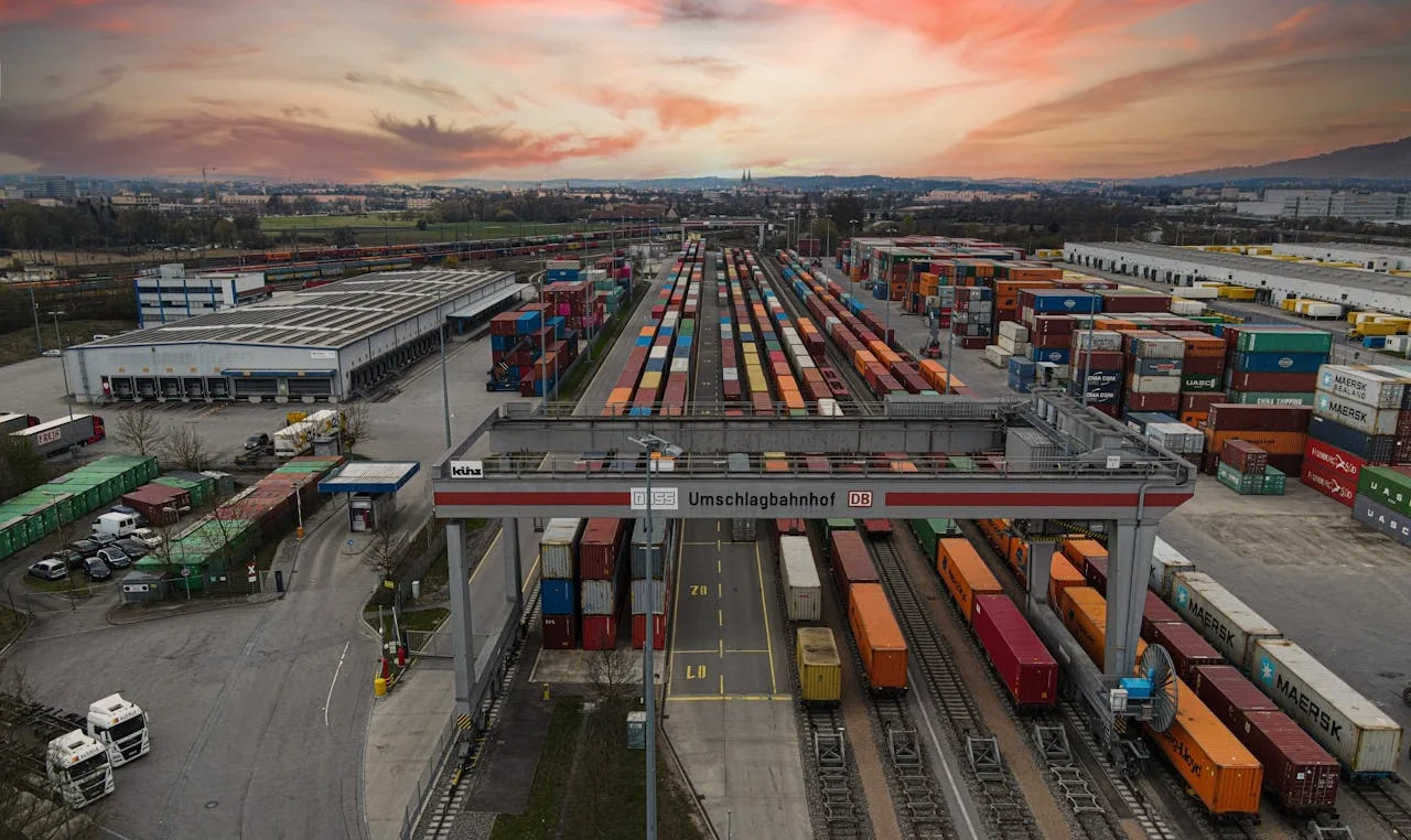 Terminal logistique intermodal avec trains de fret, conteneurs et infrastructures ferroviaires, illustrant l’intégration des modes de transport et l’optimisation des chaînes logistiques.